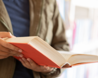 libro rilegato tenuto in mano da un uomo non visibile