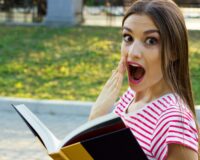 ragazza che guarda in camera mentre legge un libro
