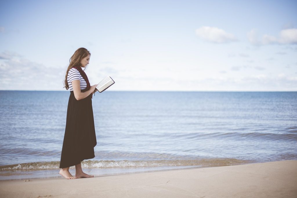 Persona che legge un libro in riva al mare mantenendo una postura rilassata e respirazione naturale.